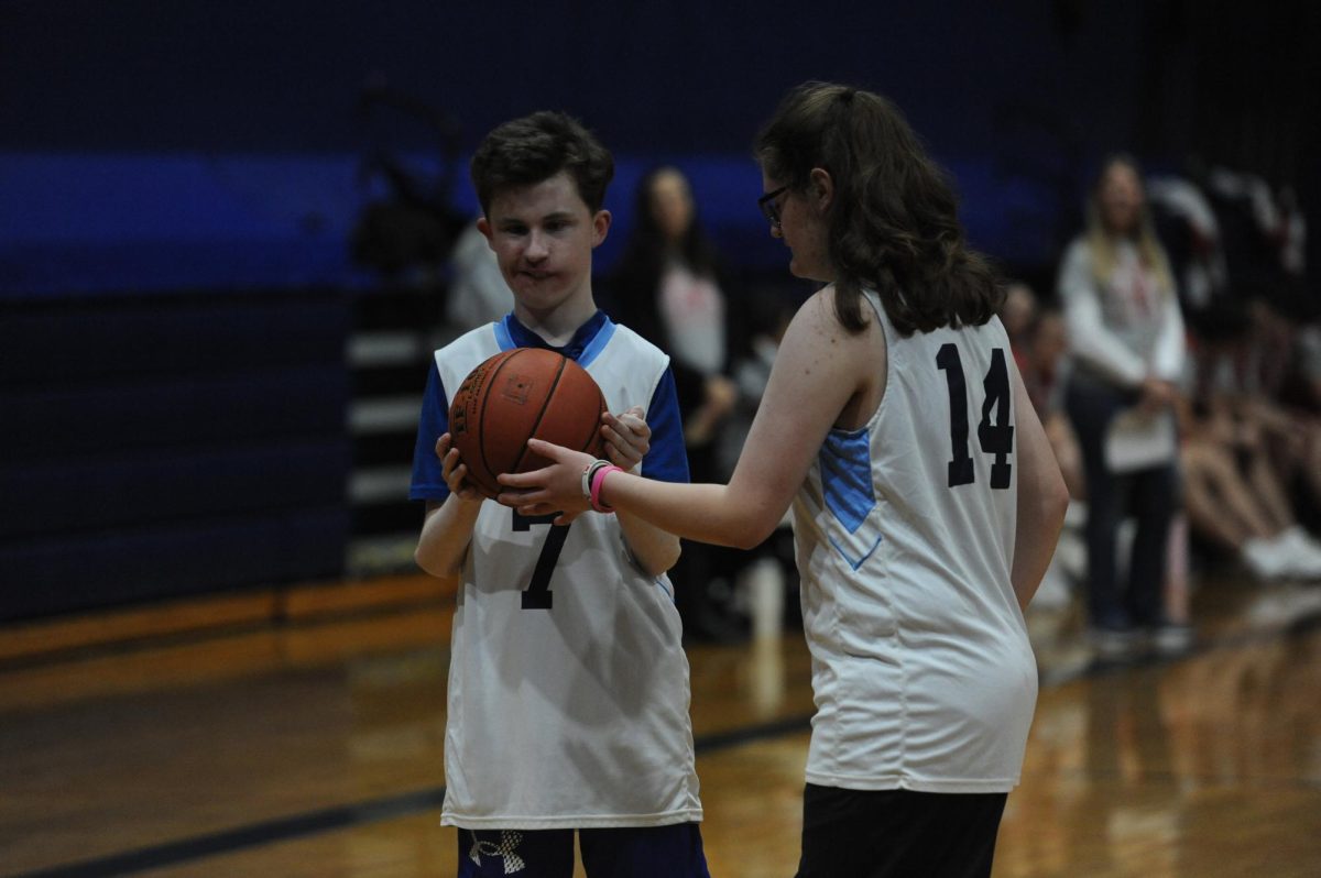 Kendall Clark aiding Brady Robinson in a unified basketball game. (Photo creds: Lani Silversides)